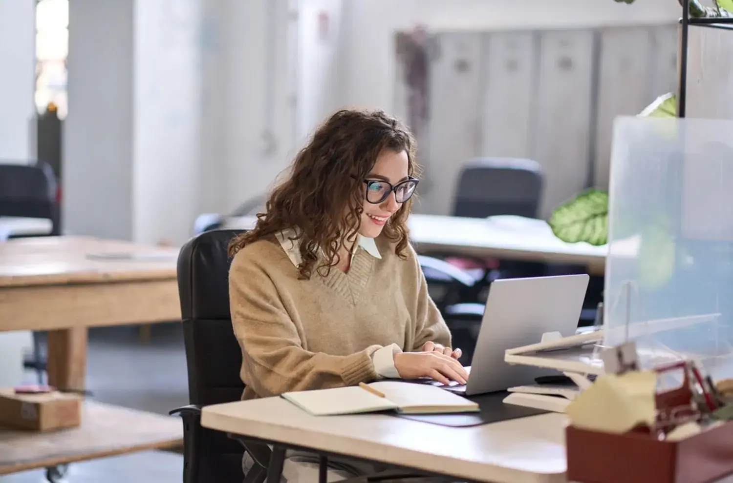 young happy professional business woman employee sitting at desk working on laptop in modern style